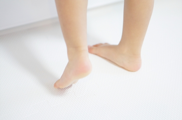 白い床の上で裸足の子どもがつま先立ちをしている様子。はだし保育で育まれる足の発達とバランス感覚。