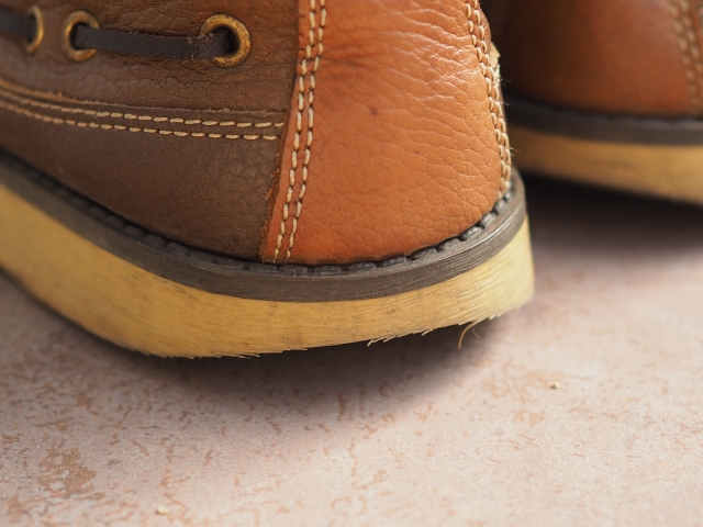 茶色い革製の靴のかかと部分のクローズアップ写真。かかとのゴム部分が擦り減り始めている。