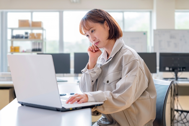 パソコン作業中に前かがみの姿勢になっている女性の様子