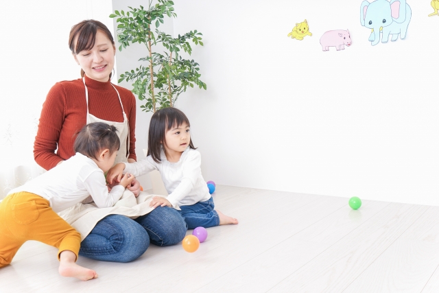 室内で子どもと遊ぶ女性。冷えやすい冬の足元を気にかけている様子。